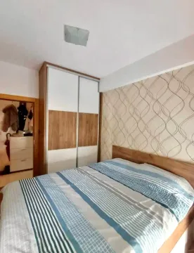 Spavaća soba sa bračnim krevetom, plakarom i tapetom na zidu. - image 5