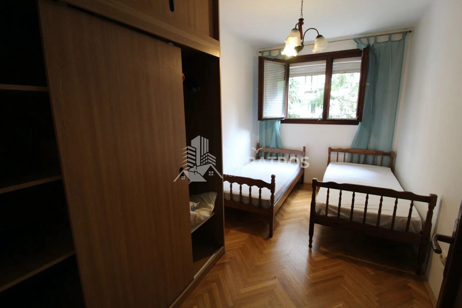 Spavaća soba sa dva kreveta i velikim drvenim ormarom.