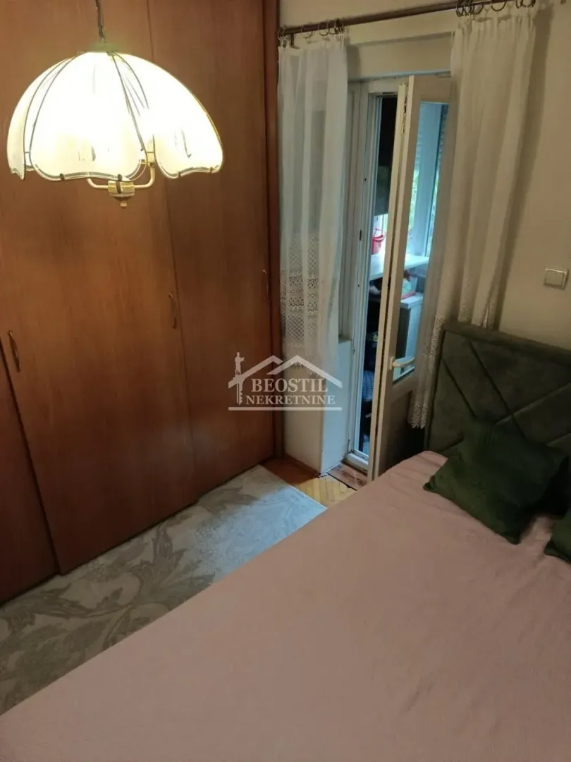 Nameštena spavaća soba sa velikim ormanom i izlazom na terasu.