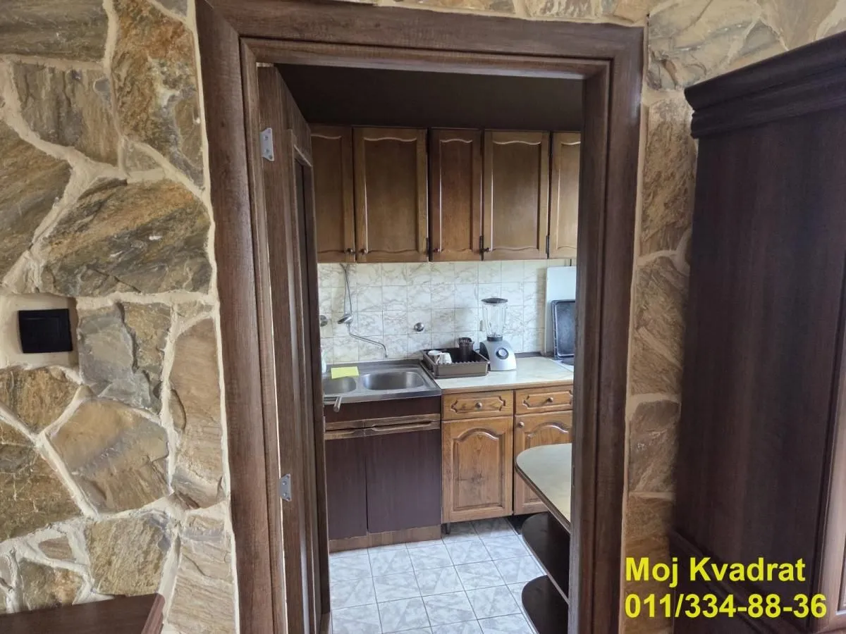 Pogled kroz vrata na manju kuhinju sa drvenim elementima.
