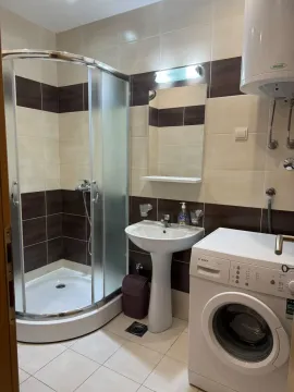 Bathroom with a shower cabin, sink, mirror, and washing machine. - image 4