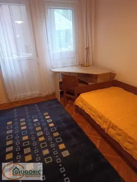 Manja spavaća soba sa krevetom, radnim stolom i prozorom sa zavesama. - image 6