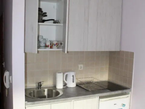 Smaller kitchen with a sink, cabinetry, and a small refrigerator. - image 6