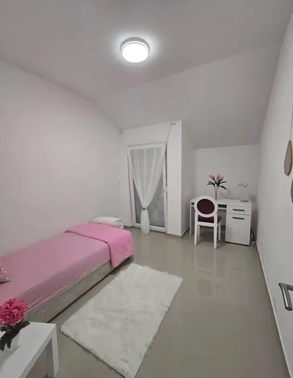 Manja spavaća soba sa krevetom, radnim stolom i izlazom na terasu.