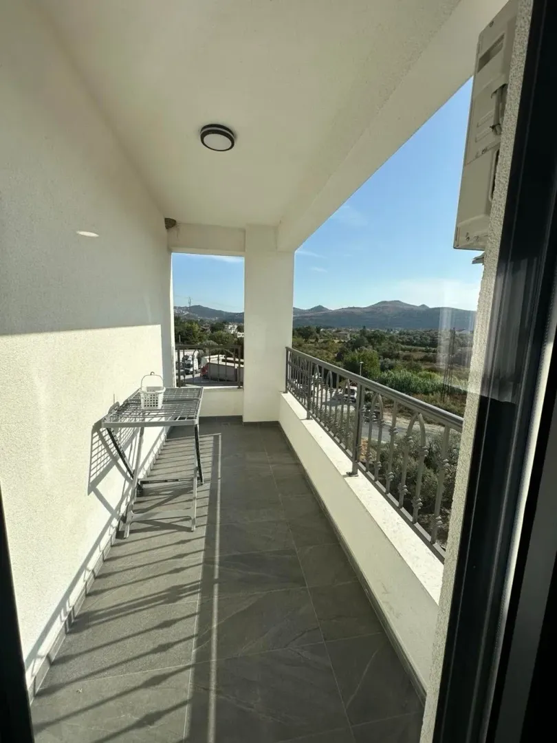 Dugački balkon sa metalnom ogradom i pogledom na okolni pejzaž.