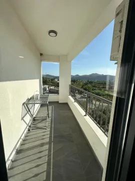 Dugački balkon sa metalnom ogradom i pogledom na okolni pejzaž. - image 9