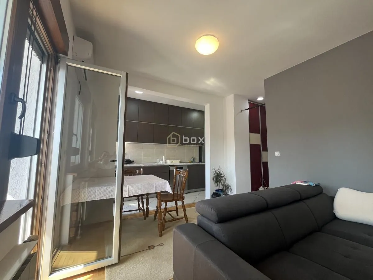 Living room with a sofa and a view towards the kitchen with dining area.