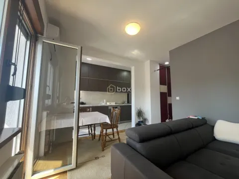 Living room with a sofa and a view towards the kitchen with dining area. - image 2
