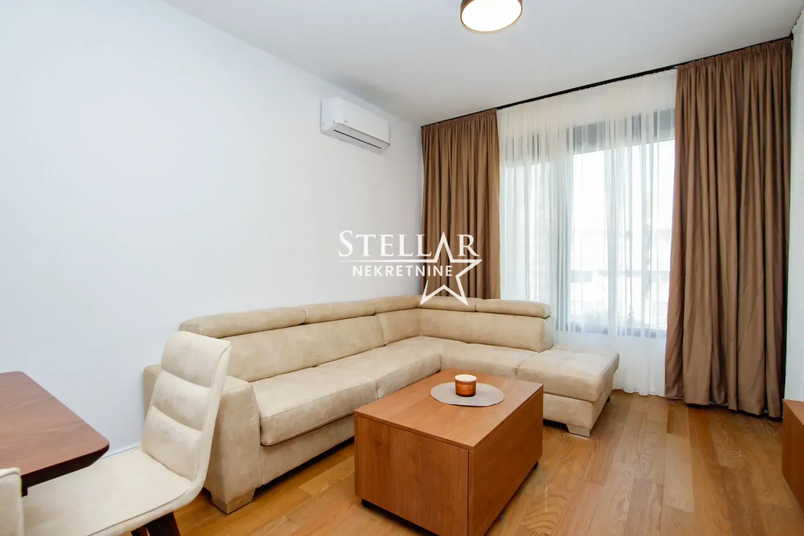 Living room with a corner sofa, wooden coffee table, and a window with curtains.