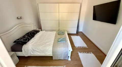 Nameštena spavaća soba sa bračnim krevetom, velikim garderoberom i televizorom na zidu. - image 9