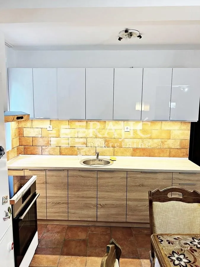 Small kitchen with white upper cabinets and wooden lower cabinets.