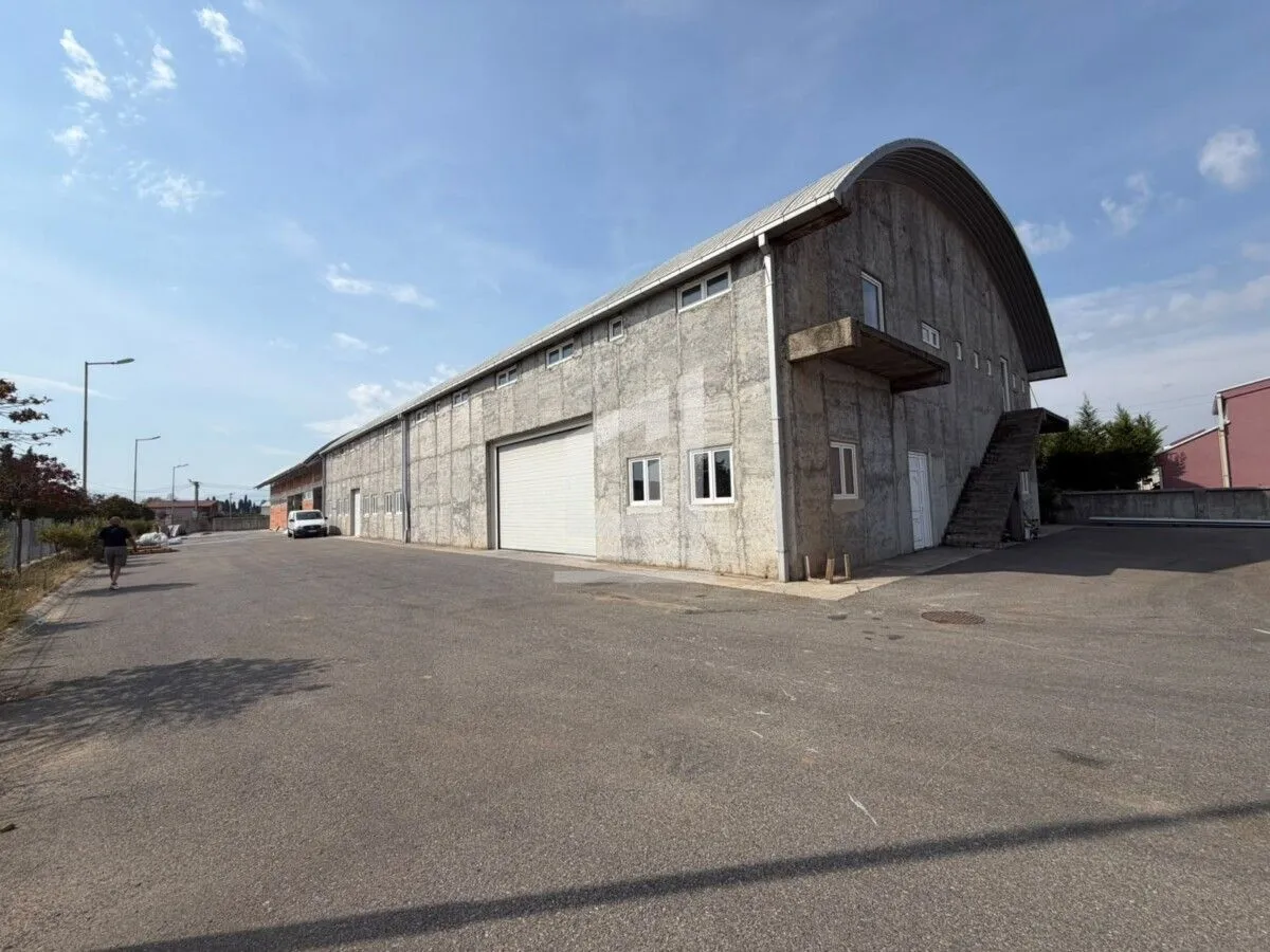Exterior view of a large industrial warehouse with a paved yard.