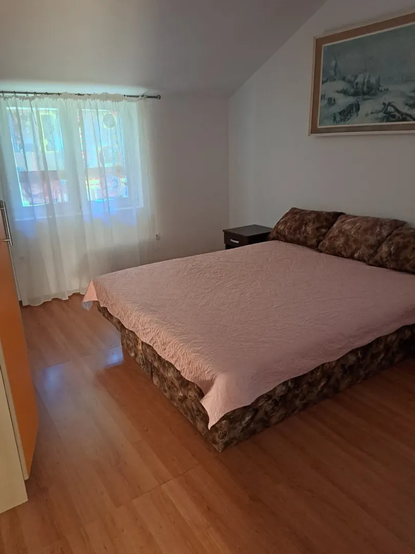 Bedroom with a double bed, bedside table, and a window with curtains.