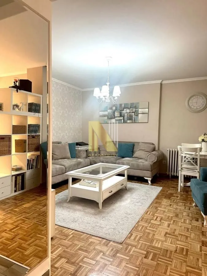 Uređena dnevna soba sa garniturom i trpezarijskim stolom.