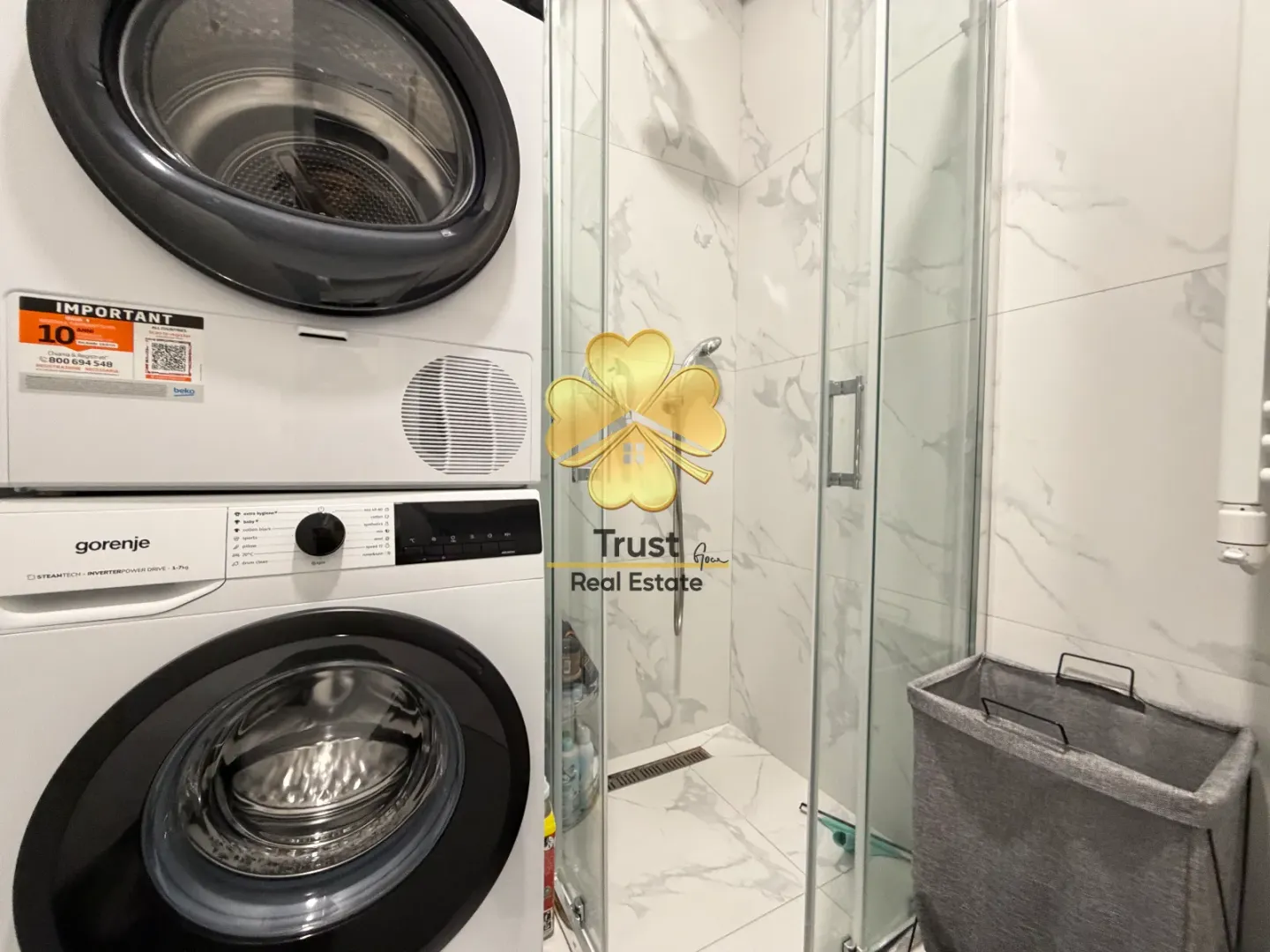 Modernly equipped bathroom with a shower cabin and a washing machine.