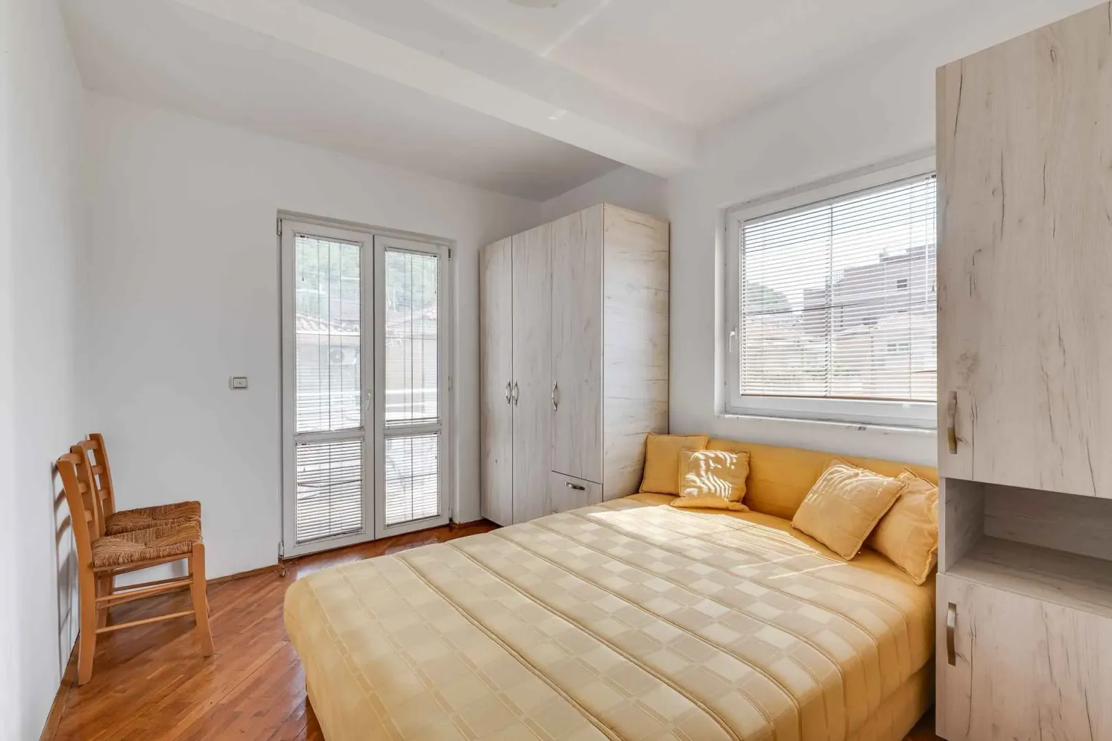 Bright bedroom with a double bed, wardrobes, and balcony access.