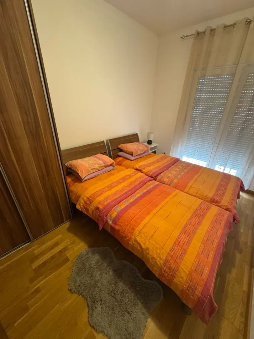 Spavaća soba sa dva singl kreveta i ormarom.