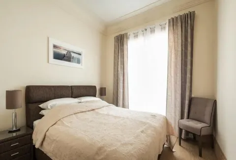 Furnished bedroom with a double bed, bedside tables, and an armchair. - image 3