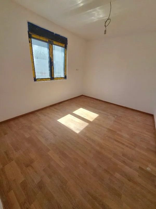 Prazna neopremljena soba sa laminatom na podu i jednim prozorom.