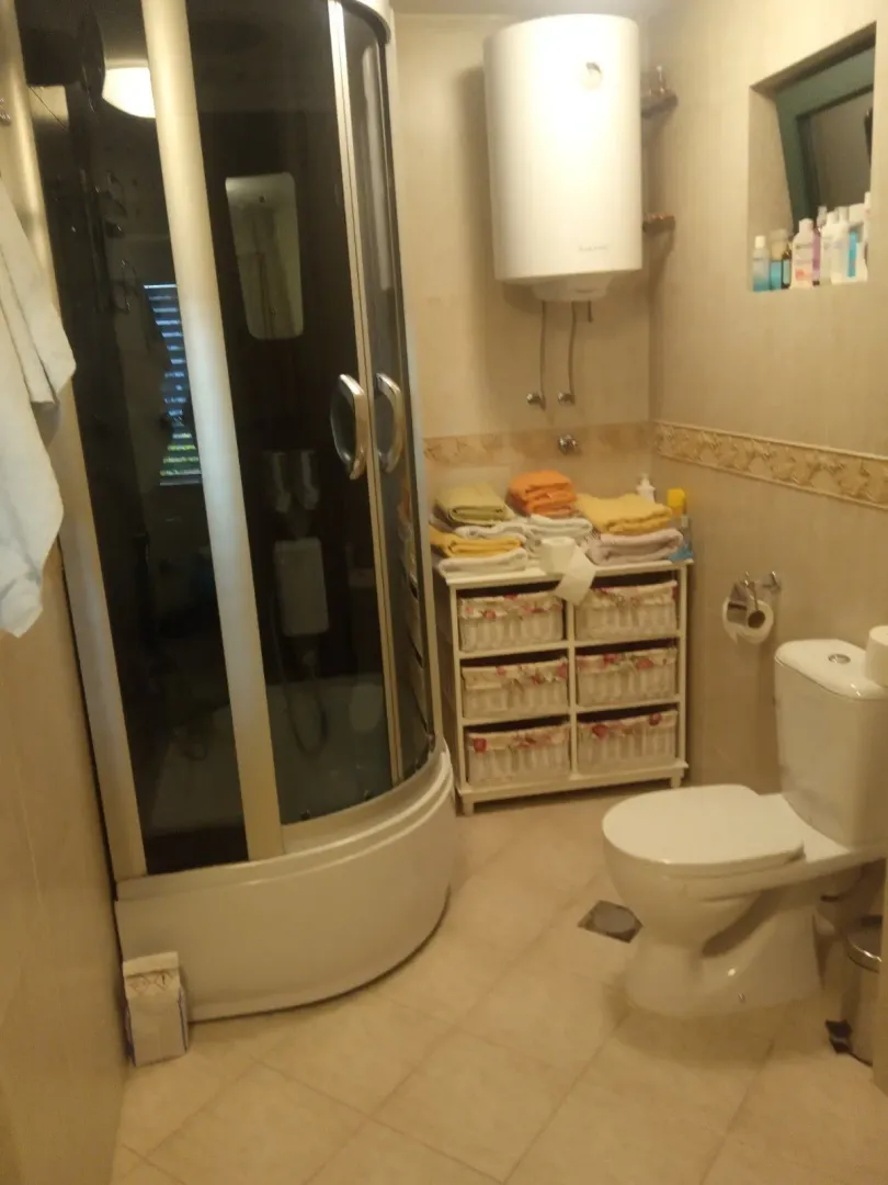 A bathroom with a shower cabin, toilet, and water heater.