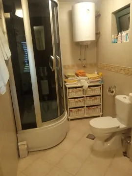 A bathroom with a shower cabin, toilet, and water heater. - image 12