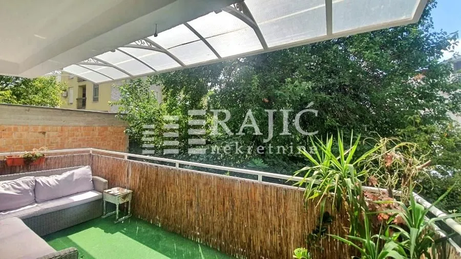 Furnished terrace with seating furniture and a view of greenery.