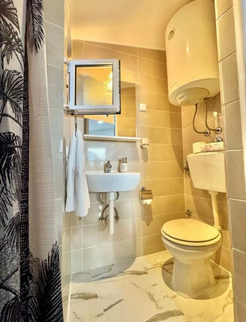 Small bathroom with a sink, toilet, and water heater.