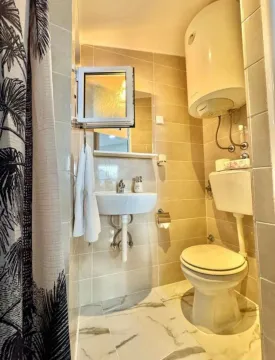 Small bathroom with a sink, toilet, and water heater. - image 5