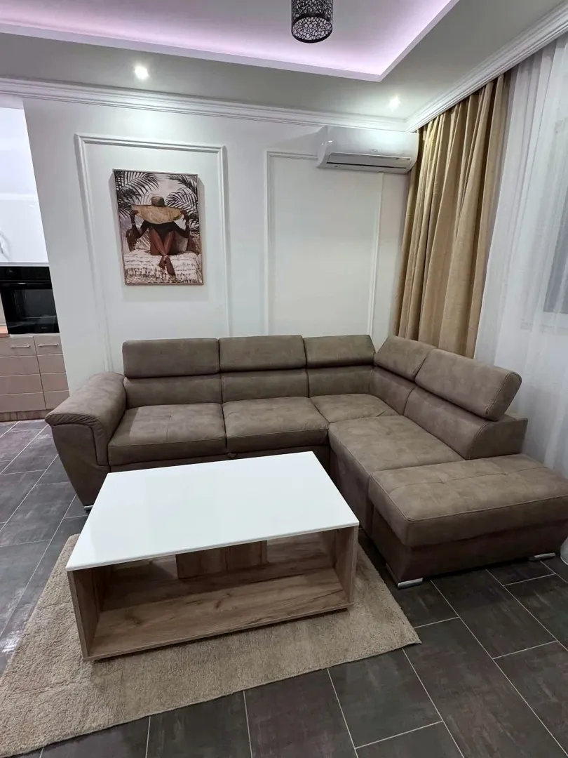 Living room with a sectional sofa, coffee table, and air conditioning unit.
