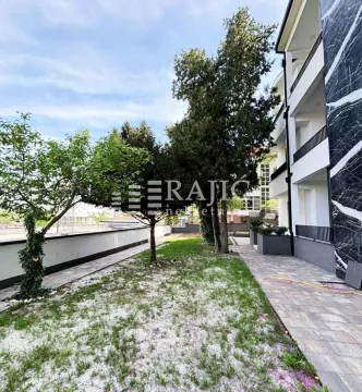 Dvorište zgrade sa travnjakom, stazom i drvećem. - image 2