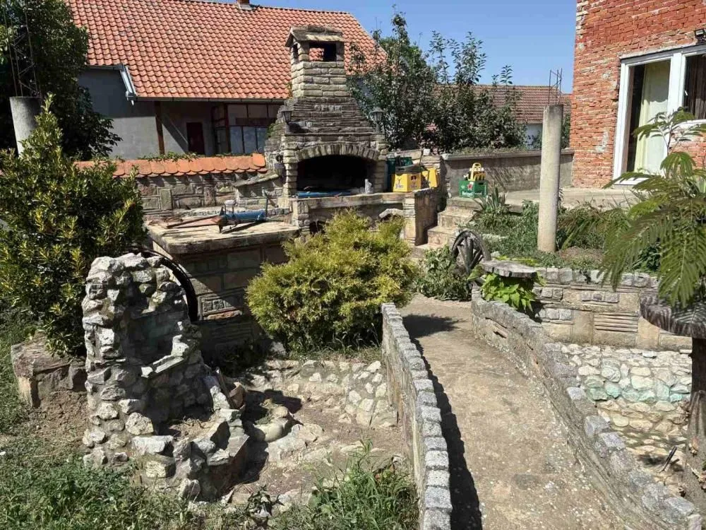 Uređeno dvorište sa kamenim roštiljem, stazama i pratećim elementima.