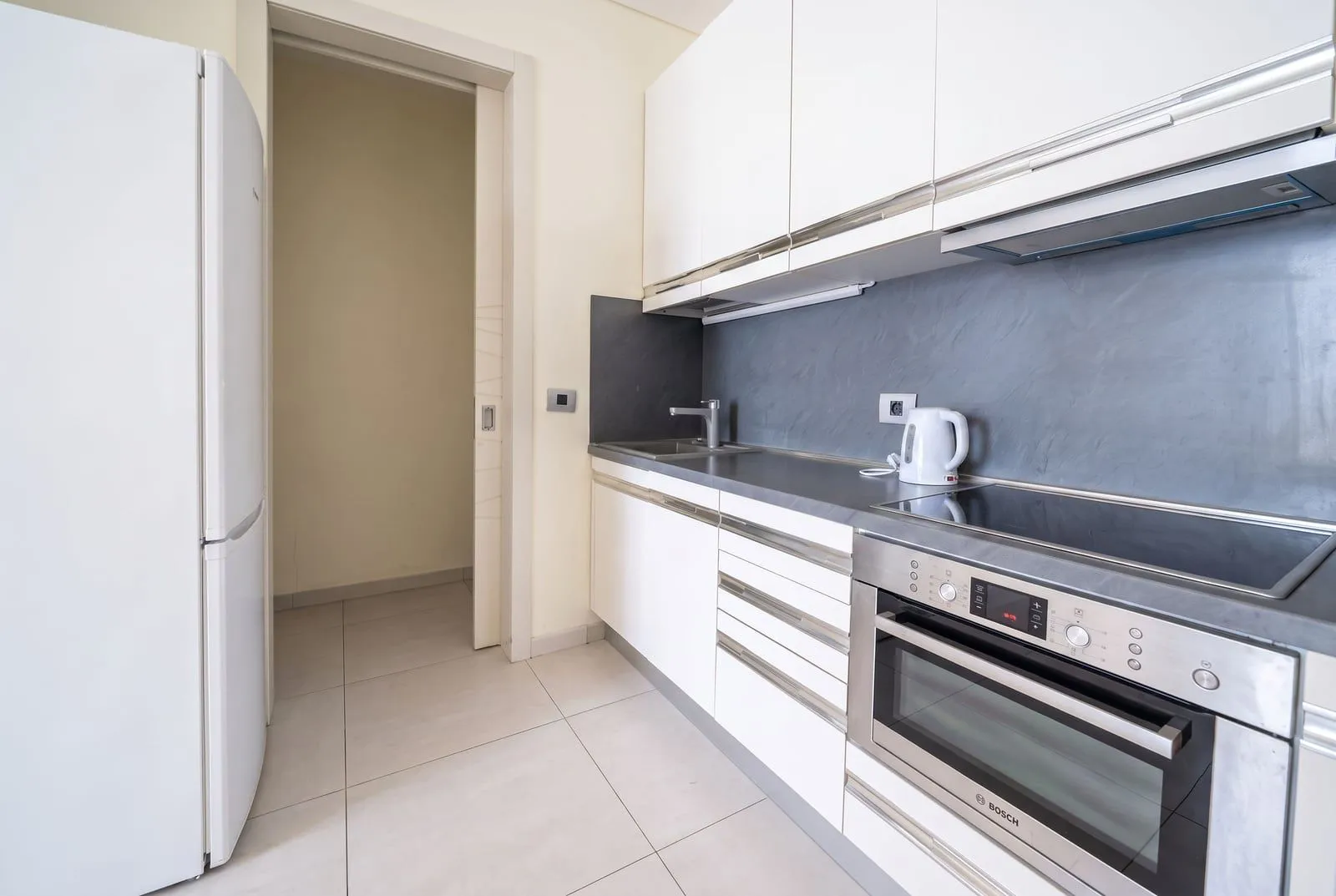 Modern white kitchen with built-in appliances and fixtures.