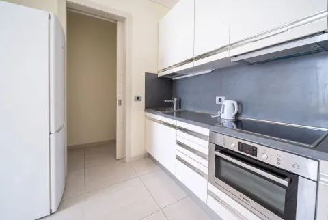 Modern white kitchen with built-in appliances and fixtures. - image 6