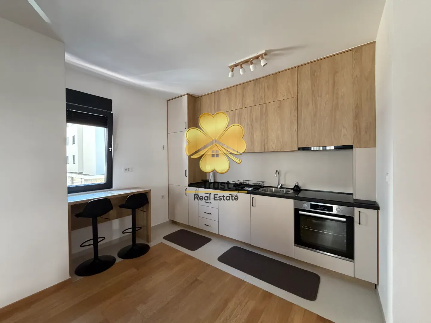 Modern kitchen with wooden cabinetry and a built-in bar with two chairs.