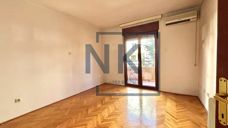 Prazna soba sa parketom i izlazom na terasu.