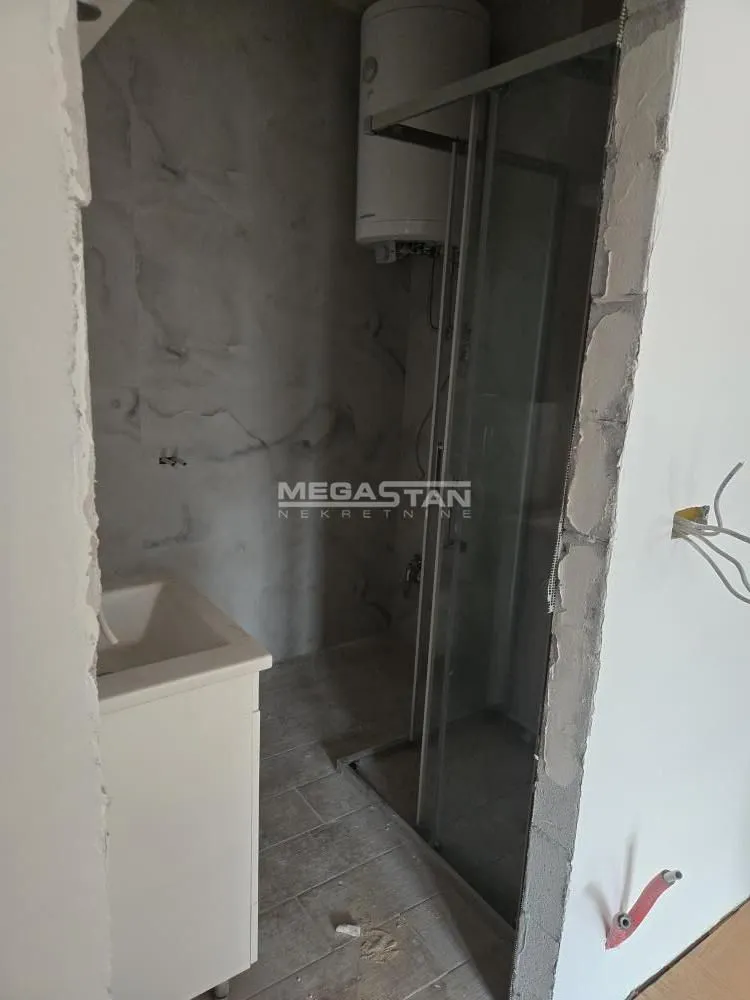 Kupatilo u fazi renoviranja sa tuš kabinom, umivaonikom i bojlerom.