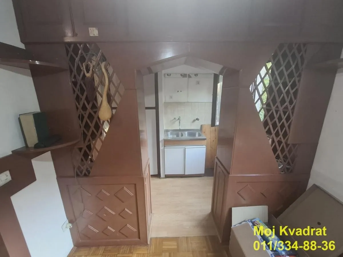 Pogled kroz drveni prolaz na manju kuhinju.