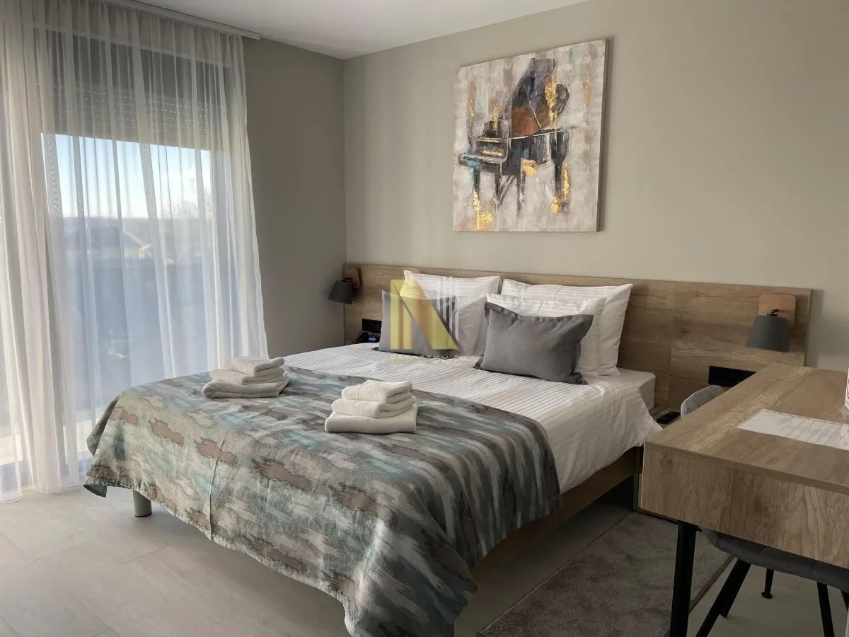 Decorated bedroom with a double bed and light furniture.