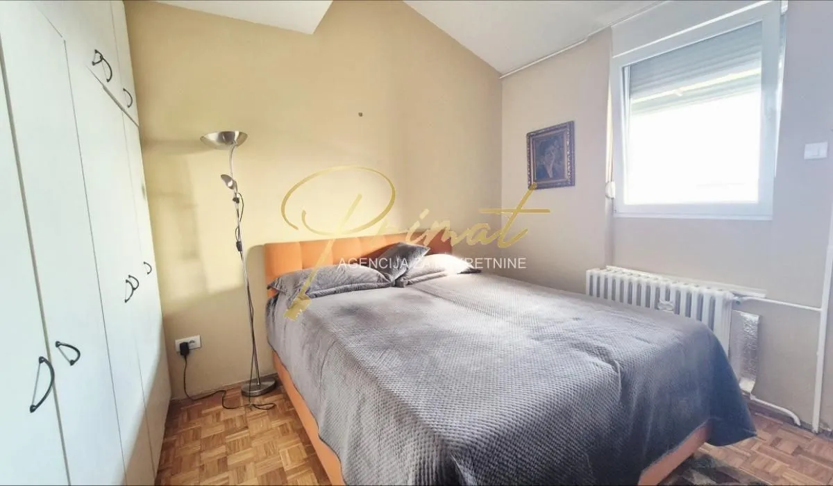 Furnished bedroom with a double bed, wardrobe, and window.