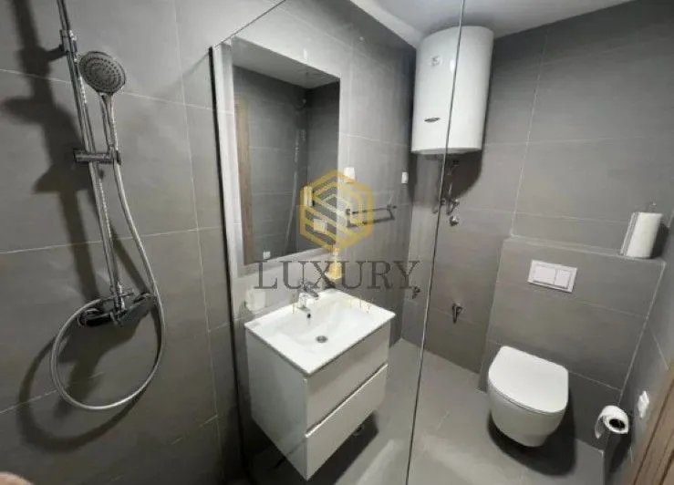 Modern bathroom with a shower cabin, washbasin, and toilet.