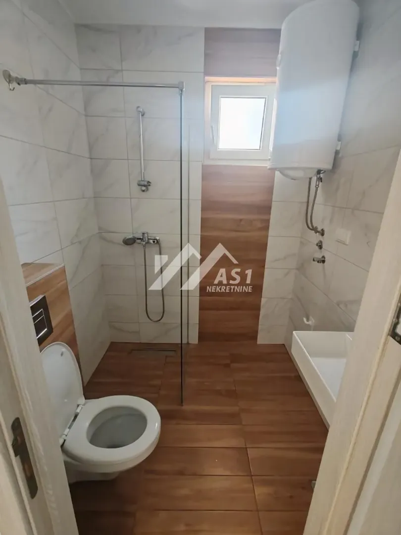 Moderno kupatilo sa tuš kabinom, WC šoljom i bojlerom.