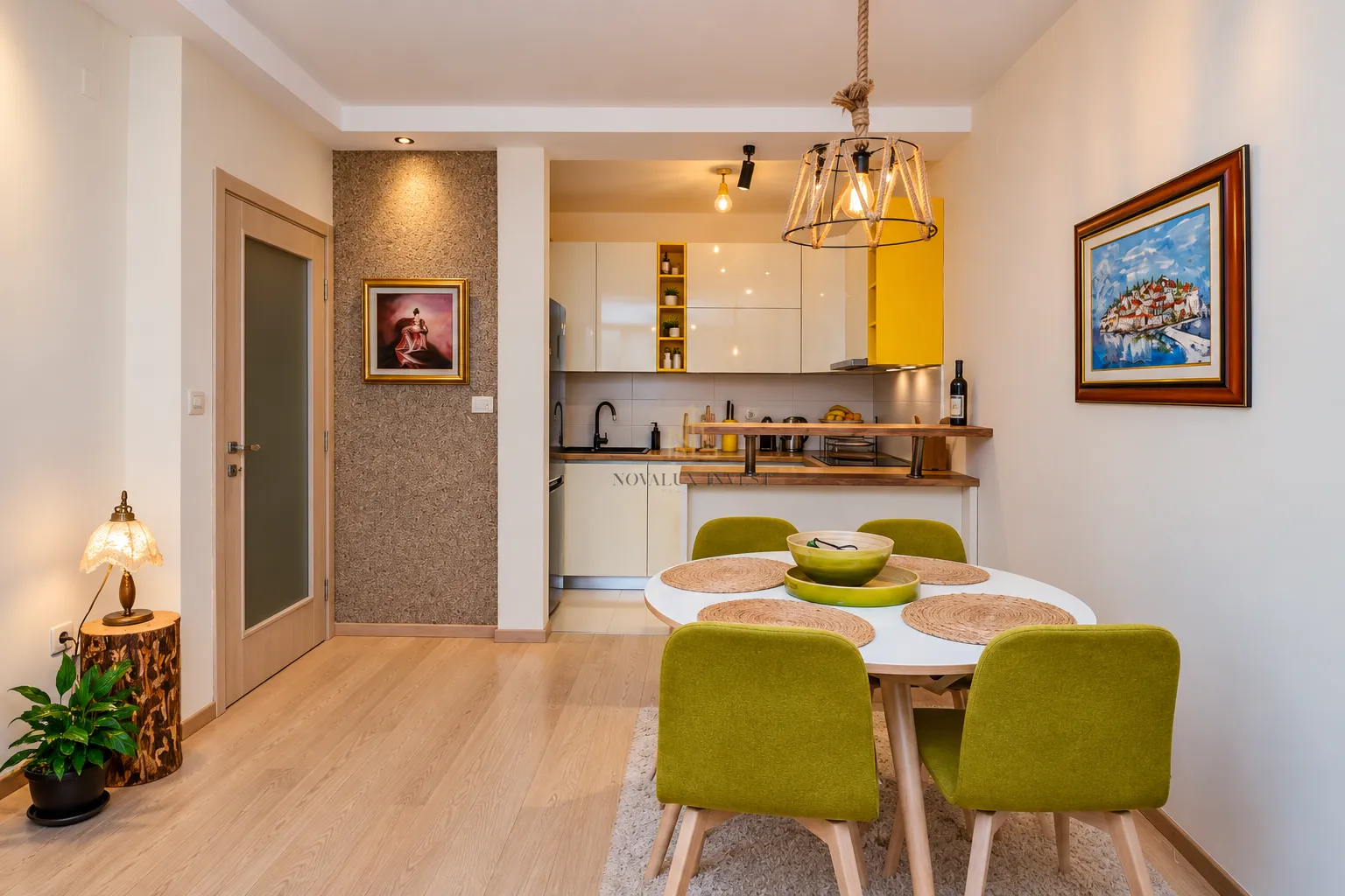 Dining area with a table and green chairs overlooking the kitchen.