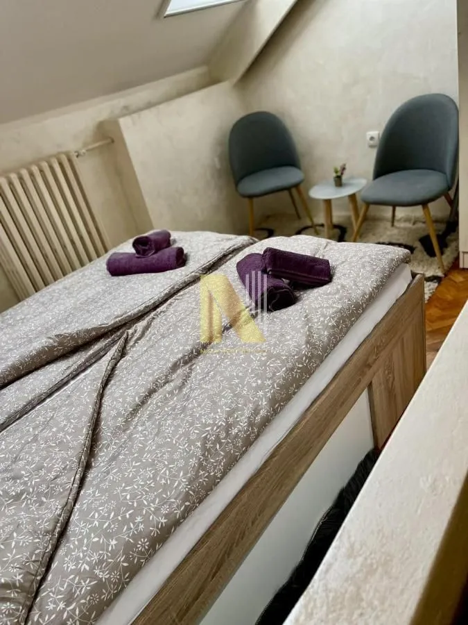 Nameštena spavaća soba sa bračnim krevetom i dve fotelje.