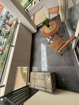 A balcony with dark floor tiles, a wooden table, and chairs. - image 16