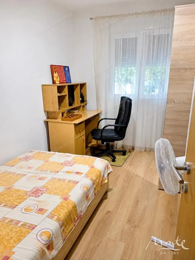 Manja spavaća soba sa krevetom, radnim stolom i plakarom.