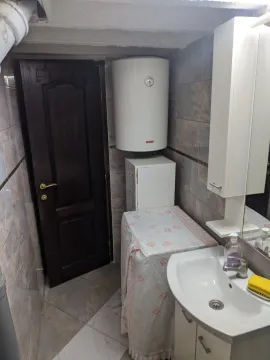A bathroom featuring a sink, water heater, and a dark door. - image 7