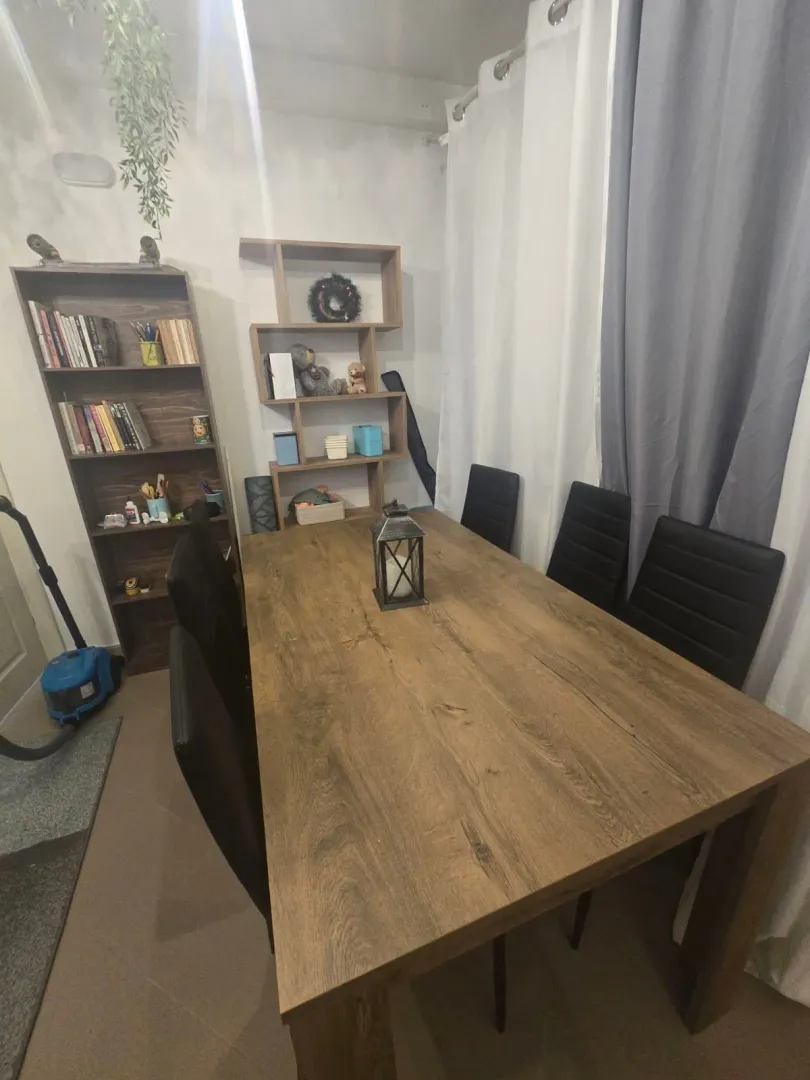 Trpezarija sa velikim drvenim stolom i policama za knjige.