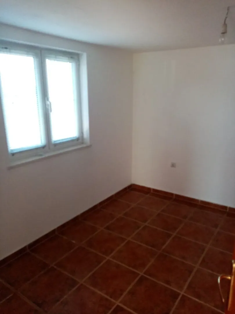 An empty room with tiled flooring and a window.