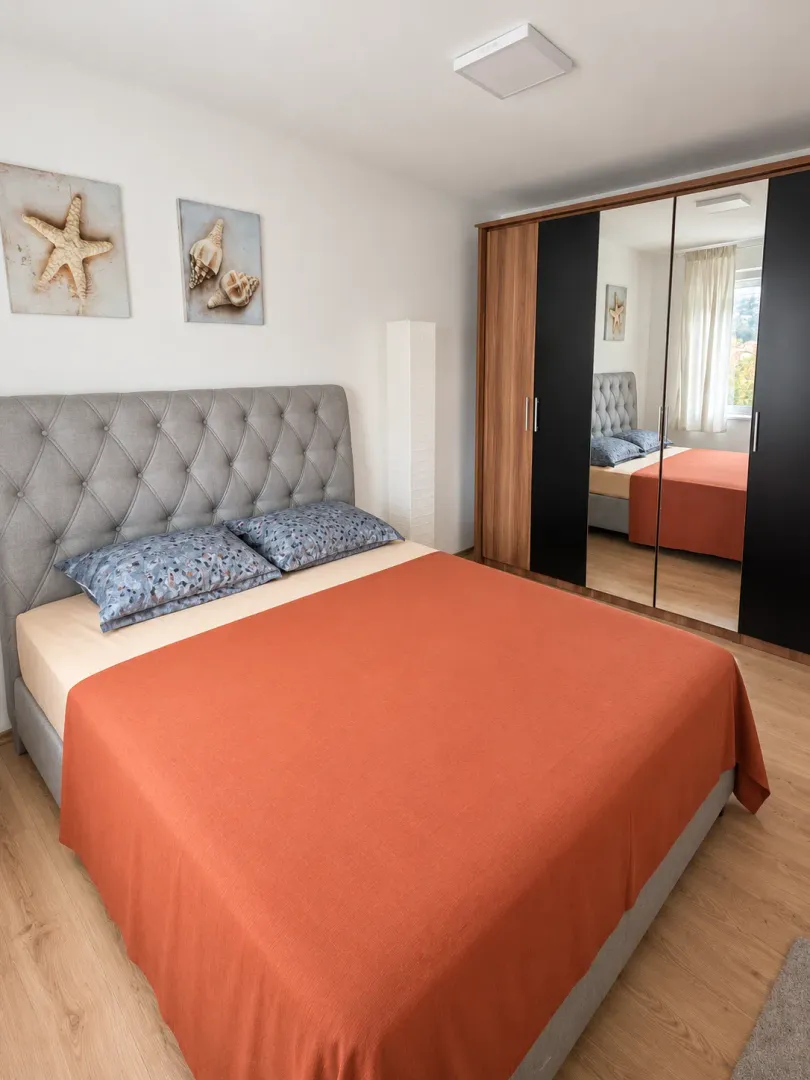 Furnished bedroom with a double bed and a large mirrored wardrobe.
