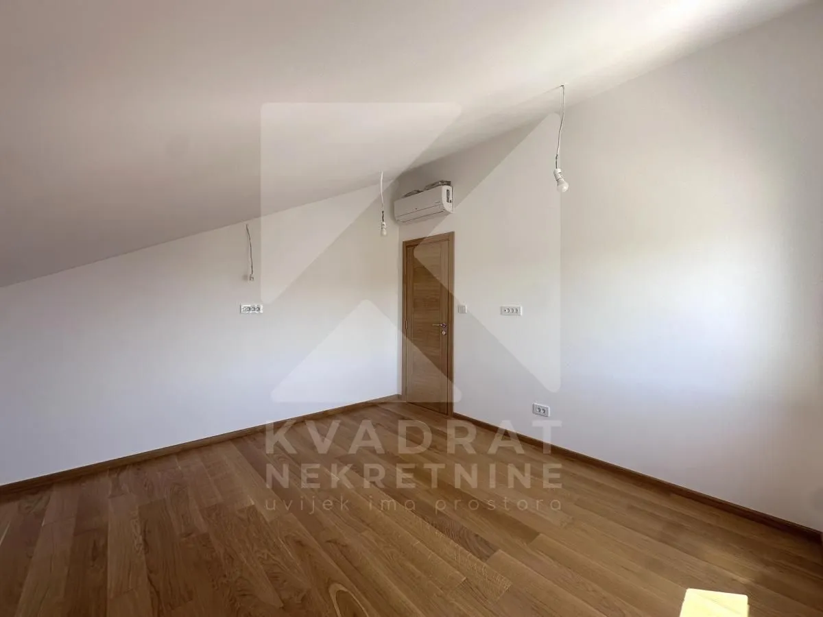 Empty attic room with wooden flooring and a door.